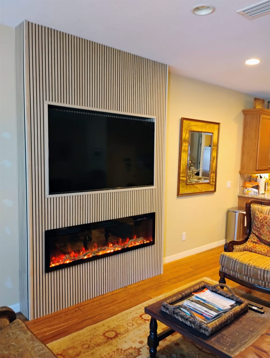 Finished wood slat feature wall with a mounted TV and built-in electric fireplace