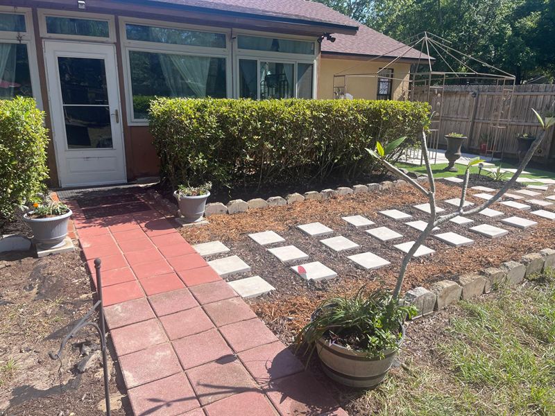 The same area with a new red paver walkway, stone-bordered bed, fresh mulch and matching stepping stones