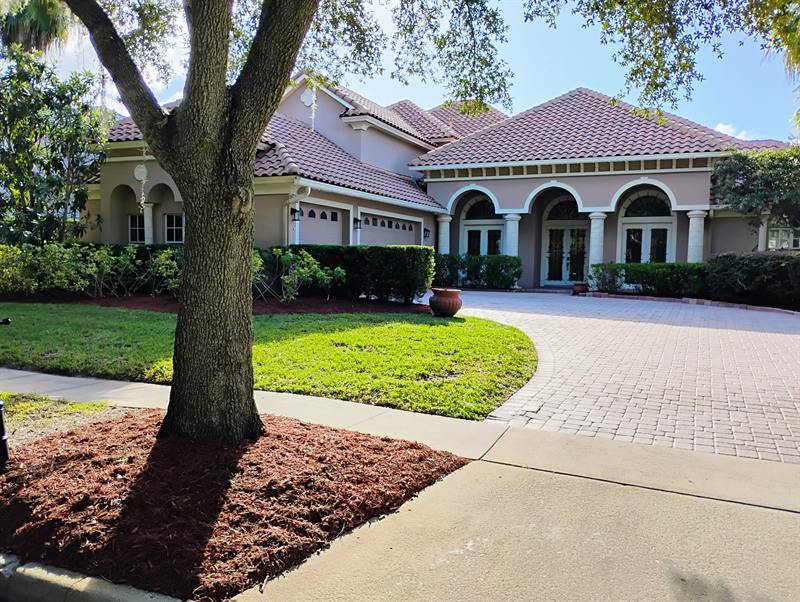 Large oak with fresh mulch beside a paver driveway at an estate