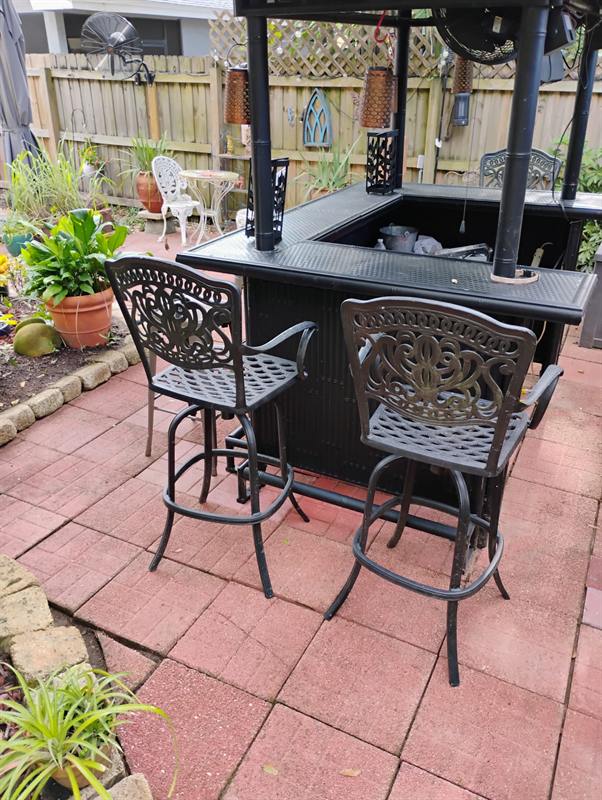 Restored red paver patio with a bar table, stools and tiki torches