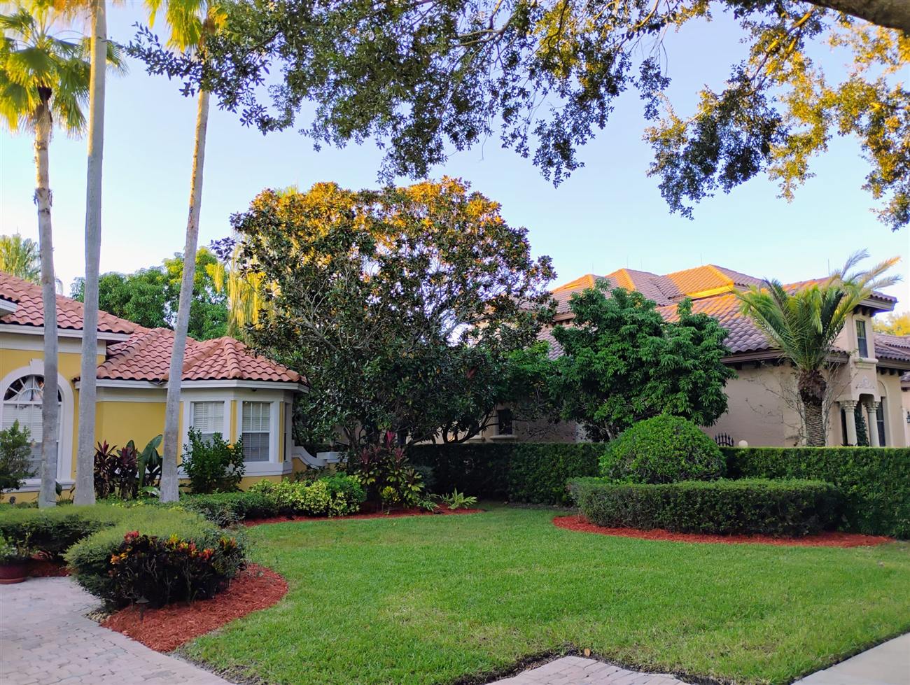 Freshly landscaped front yard with a manicured lawn, trimmed hedges and red mulch beds